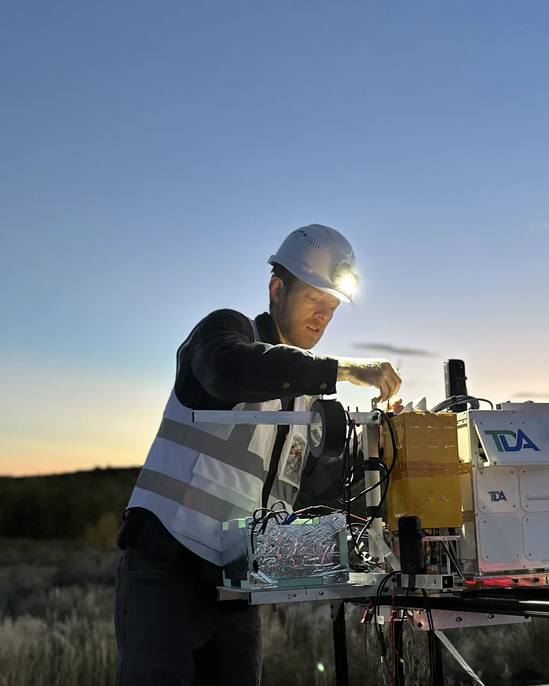 StratoStar engineer integrating payload electronics at dusk before a near-space flight test