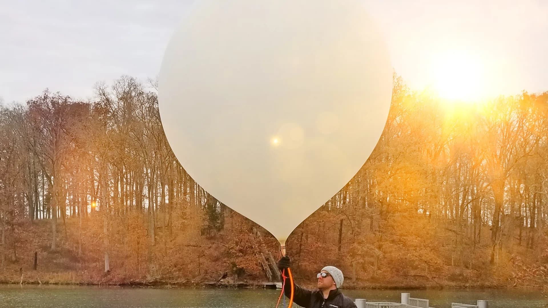 Launching a weather balloon at sunset beside a lake