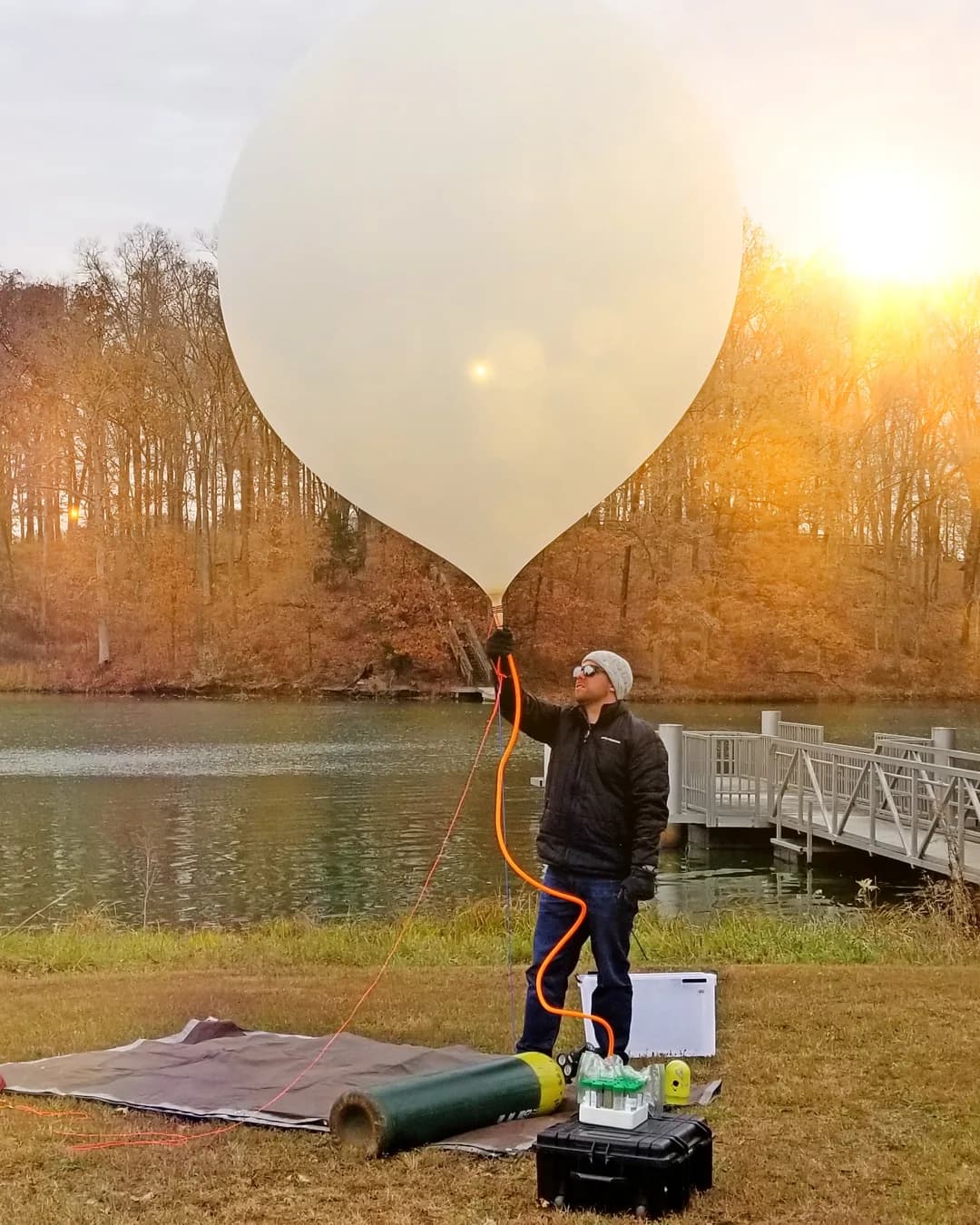 Launching a weather balloon at sunset beside a lake