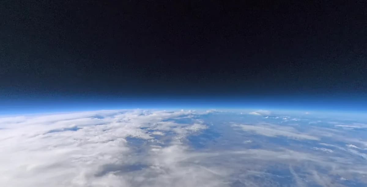 The view from a SHARE flight near 100,000 feet: the curve of the Earth, clouds, and the black sky above.