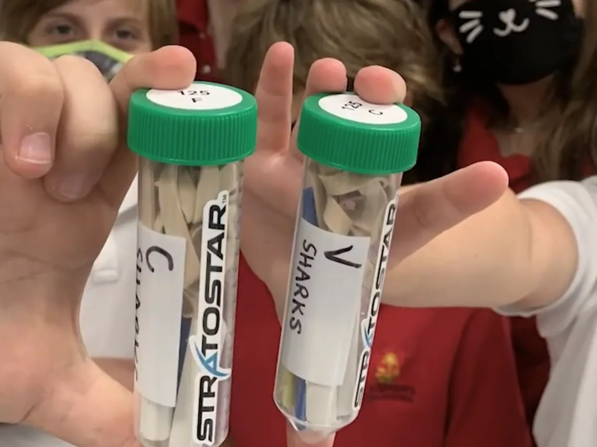 Students hold up their two SHARE capsules, one labeled for flight and one for the ground control.